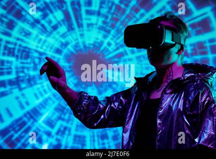Man with tattoo on neck standing against cyclical background and gesturing hand in virtual space Stock Photo