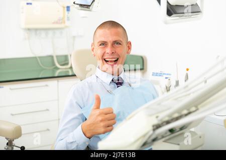 Male patient showing thumb up after dental treatment in clinic Stock Photo