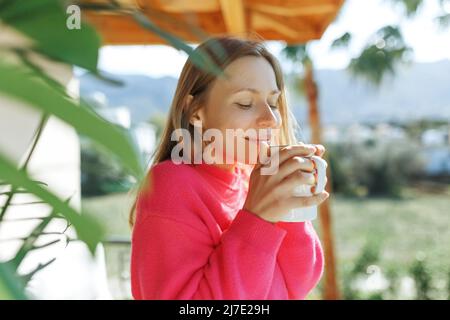 Young woman enjoying the view from apartment,drinking morning coffee on the balcony. Stock Photo