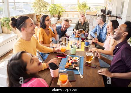 Young people having a great time in bar. Friends smiling fun and sitting in a coffee shop, drinking coffee and enjoying together. Stock Photo