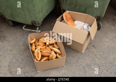 Carton box with bread in it, near a waste container in Israel. left for homeless and hungry people in the city. Stock Photo