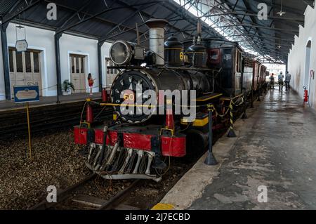 Front view of a deactivated Baldwin Locomotive Works Nº 60 displayed at Sao Joao del Rei train station with some rail cars attached behind. Stock Photo