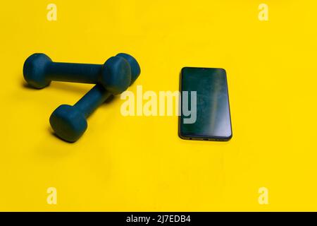 Text yellow for with a phone dumbbells Blue background space on isolated iron, from fit lifting in bodybuilding from barbell gym, kettle color. Power Stock Photo
