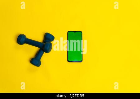 On a Blue for background yellow space phone dumbbells with text space iron, for fit health for dumbbell from heavy strength, sport color. Vivid pound Stock Photo