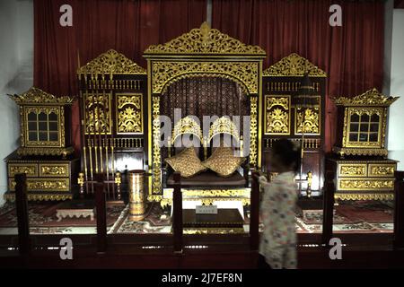 A child standing in front of the throne of the Sultanate of Palembang, photographed at Sultan Mahmud Badaruddin II Museum in Palembang, South Sumatra, Indonesia. Stock Photo