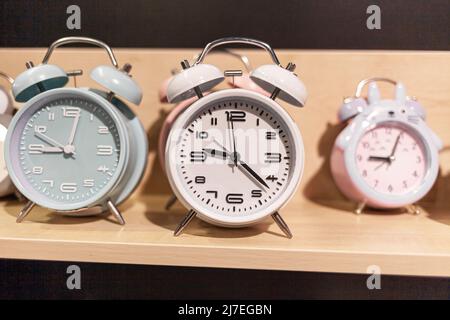 Round alarm clock on the store shelf close-up. Sale of various watches and alarm clocks of different colors. Retro alarm clock on the table, vintage t Stock Photo