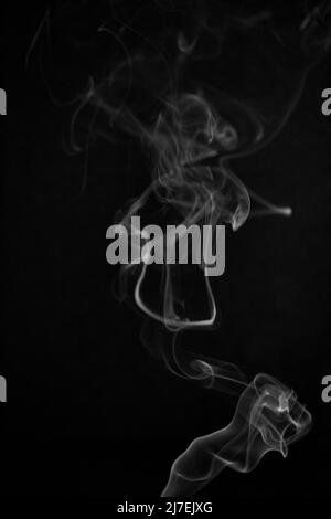 Black and white swirling, ascending smoke pattern on a black background, photo could be used as a background, smoke texture, abstract, or general stoc Stock Photo