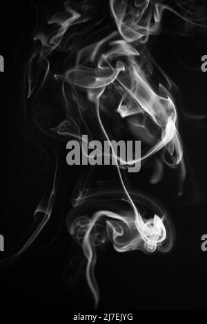 A black and white swirling, ascending smoke pattern on a black background, photo could be used as a background, smoke texture, abstract, or general st Stock Photo