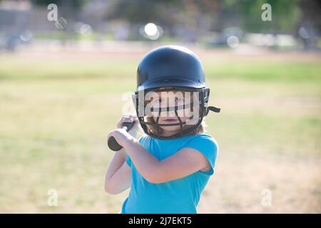 Little child baseball player focused ready to bat. Sporty kid players in helmet and baseball bat in action. Stock Photo