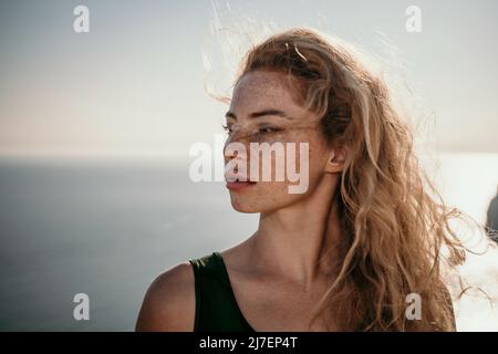 Close up shot of beautiful young caucasian woman with curly blond hair and freckles looking at camera and smiling. Cute woman portrait posing on a Stock Photo