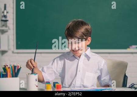 Child boy drawing cute draw using colored pencils at school or kindergarten. Childhood learning, kids artistics skills. Stock Photo