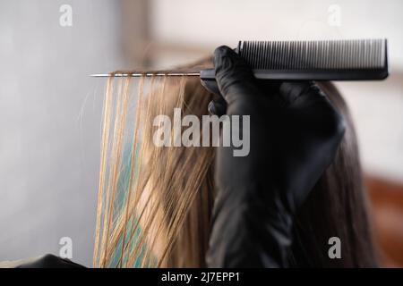 Hairdresser Dyes the hair, he separates the strands hair in preparation for coloring or highlighting. brunette Came to the beauty salon. Stock Photo