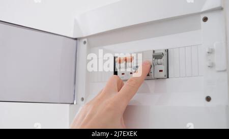 Man turns on toggle switch with hand closeup Stock Photo