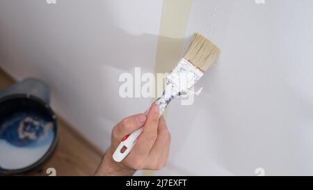 Manual worker holding brush and painting with white on wall of house Stock Photo
