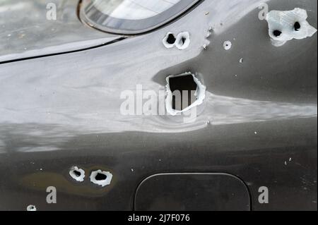 Close-up of the body of the shelled car. A sedan with through holes from shrapnel and bullets. The war in Ukraine 2022. Russian aggression. Shelling o Stock Photo