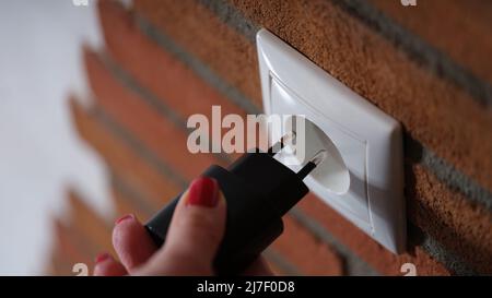 Woman holding hand and inserting plug into socket closeup Stock Photo