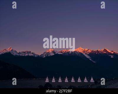 white pagodas of feilai temple with meili snow mountain at sunrise in background in china's yunnan province Stock Photo