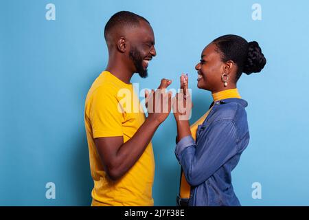 Couple holding fingers crossed to wish for good luck and fortune in front of camera. Positive girlfriend and boyfriend hoping for miracle, feeling excited about future. Superstitious lovers Stock Photo