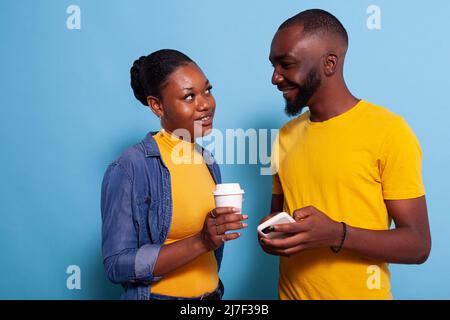 Modern couple with smartphone enjoying laugh and looking at each other. Cheerful lovers having fun with technology on mobile phone and browsing internet. People in relationship. Stock Photo