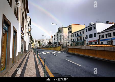 FUNCHAL, MADEIRA ISLAND - February 20, 2022: Funchal city street after the rain with a beautiful rainbow Stock Photo