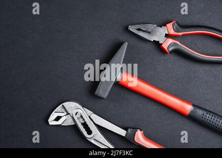 Set of renovation tools. Instruments for repair and maintenance. Hammer, wrench and tongs on black background, top view flat lay Stock Photo
