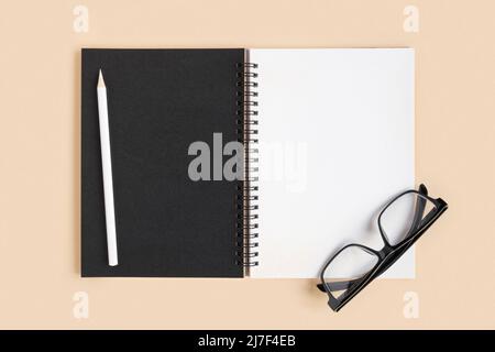 Notebook with pencil. Open notebook on beige color background, office spiral notepad on table with blank pages. Top view. White Page for write. Stock Photo
