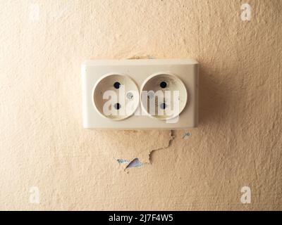 Double socket on the wall with a crack near it Stock Photo