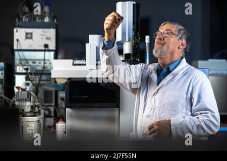Senior scientist in a chemistry lab carrying out research - looking at gas chromatography samples, preparing the analysis on a modern gas chromatograp Stock Photo