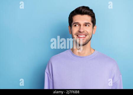 Photo of funny young brunet guy look promo wear sweatshirt isolated on blue color background Stock Photo