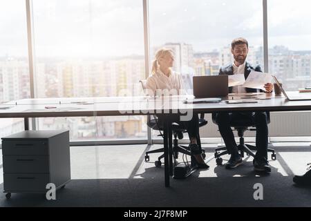 Two middle age confident business workers. Working together with smile on face using laptop Stock Photo