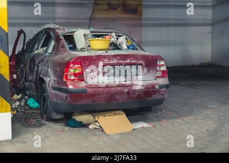 photo of a destroyed car with trash in the underground parking lot full shot . High quality photo Stock Photo