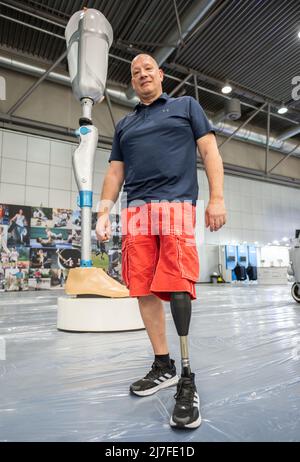 Leipzig, Germany. 09th May, 2022. Mathias Börner, Ottobock sales representative for Saxony and Thuringia, stands in front of an oversized model of a leg prosthesis. The Duderstadt-based company Ottobock is displaying a four-meter-high model of the C-Leg leg prosthesis to mark its 25th anniversary at OTWorld 2022, the world's leading trade fair for orthopaedic and rehabilitation technology. It was the world's first mechatronic knee joint. The C-Leg technology has now been used in more than 100,000 fittings worldwide. Credit: Christian Modla/dpa/Alamy Live News Stock Photo