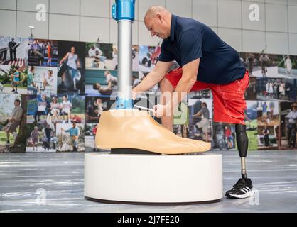 Leipzig, Germany. 09th May, 2022. Mathias Börner, Ottobock sales representative for Saxony and Thuringia, screws on an oversized model of a leg prosthesis. The Duderstadt-based company Ottobock is displaying a four-meter-high model of the C-Leg leg prosthesis to mark its 25th anniversary at OTWorld 2022, the world's leading trade fair for orthopaedic and rehabilitation technology. It was the world's first mechatronic knee joint. The C-Leg technology has now been used in more than 100,000 fittings worldwide. Credit: Christian Modla/dpa/Alamy Live News Stock Photo