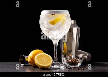 Pouring gin tonic drink into a glass on black background Stock Photo