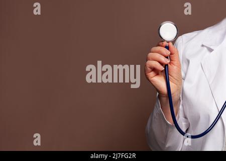 Doctor hand holding stethoscope on brown background Stock Photo
