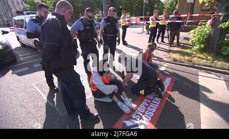 Leipzig, Germany. 09th May, 2022. Environmental activists of the group 'Last Generation' stuck themselves on the roadway and a policeman tried to remove the glue. Police task forces cordoned off the area and removed the protesters. Traffic was backed up over a wide area. Credit: Tobias Junghannß/TNN/dpa/Alamy Live News Stock Photo