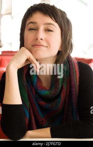 Portrait of a young beautiful brunette in a striped scarf Knitted Crochet