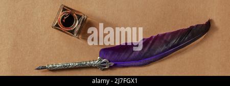 Feather quill pen with an old inkwell panorama, shot from the top on old paper Stock Photo