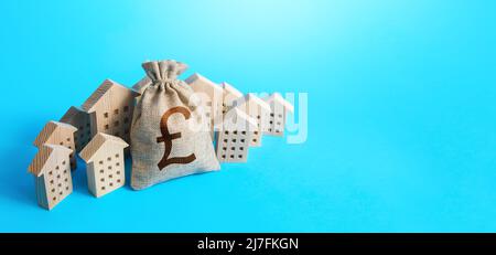 British pound sterling money bag surrounded by houses. Real estate investment. Mortgage loan. Construction industry. Property insurance. Housing appra Stock Photo