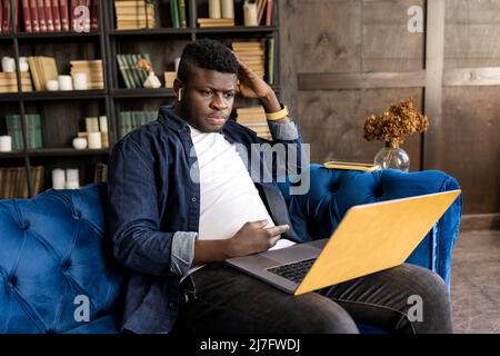 Young african american male freelancer working to coworkers on video meeting, using laptop. Stylish friendly businessman having a video meeting Stock Photo