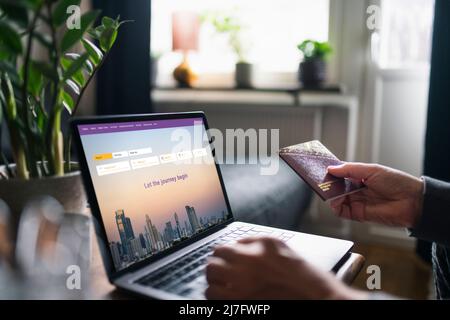 Man searching for flights on laptop and holding passport Stock Photo
