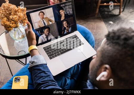 Back view Afro American business man typing on yellow laptop computer on desk, mobile phone and tablet, hold online meeting, make plan of new project Stock Photo