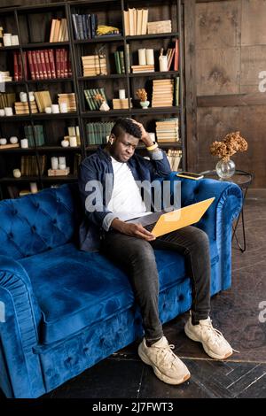 Serious African american manager wear headphones looking at laptop screen provide support to client distantly, hold online conference. Student study Stock Photo