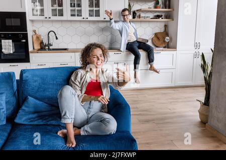 Beautiful young couple, man and woman, making selfie smiling and working on laptops while sitting at home. Happy couple in love with happiness and Stock Photo
