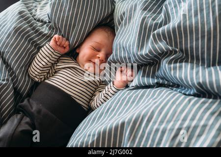 Sleeping newborn baby lying in bed Stock Photo