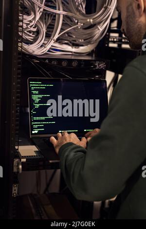 IT technician working on laptop in server room Stock Photo