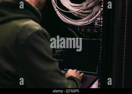 IT technician working on laptop in server room Stock Photo