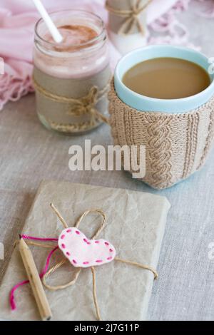 Oatmeal, flavored with yogurt, sprinkled with cinnamon in a glass jar. Next is a cup of coffee and a bottle of milk. Next is a craft notebook and a pi Stock Photo