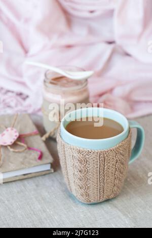 Oatmeal, flavored with yogurt, sprinkled with cinnamon in a glass jar. Next is a bottle of milk. Next is a craft notebook and a pink napkin. Stock Photo