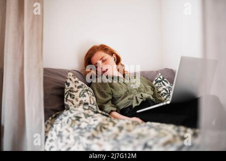 Woman sleeping on bed with laptop on laps Stock Photo